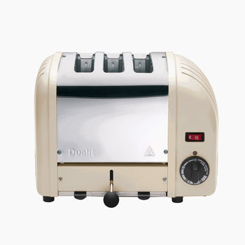 A cream Dualit 3 Slice Vario Classic Toaster with a stainless-steel body and a mechanical timer control on the front.